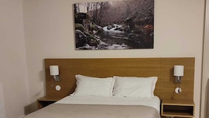 Quarto moderno com uma cama grande, duas mesas de cabeceira, uma cabeceira e um quadro na parede.