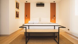 Ein modernes Schlafzimmer mit einem Bett, einem Schreibtisch und einem Stuhl. Zwei Wandklimaanlagen und zwei Wandleuchten sind angebracht.