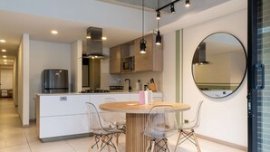 Uma cozinha moderna com uma ilha central, cadeiras transparentes e uma mesa redonda.