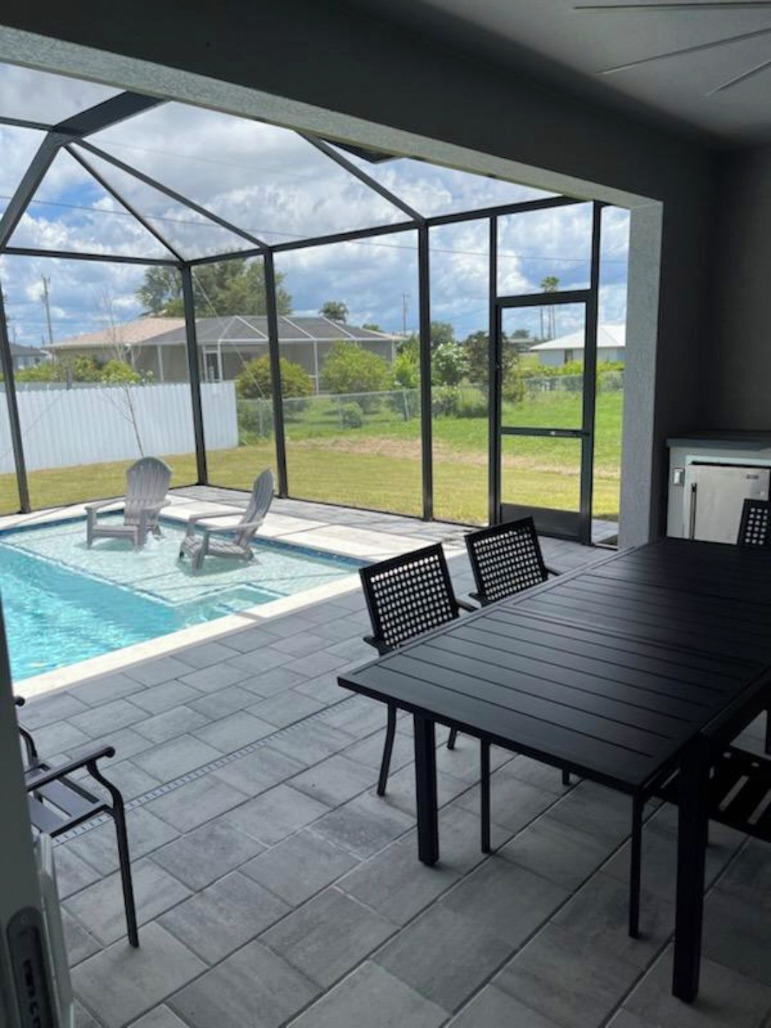 Une terrasse couverte avec une piscine, une table et des chaises.
