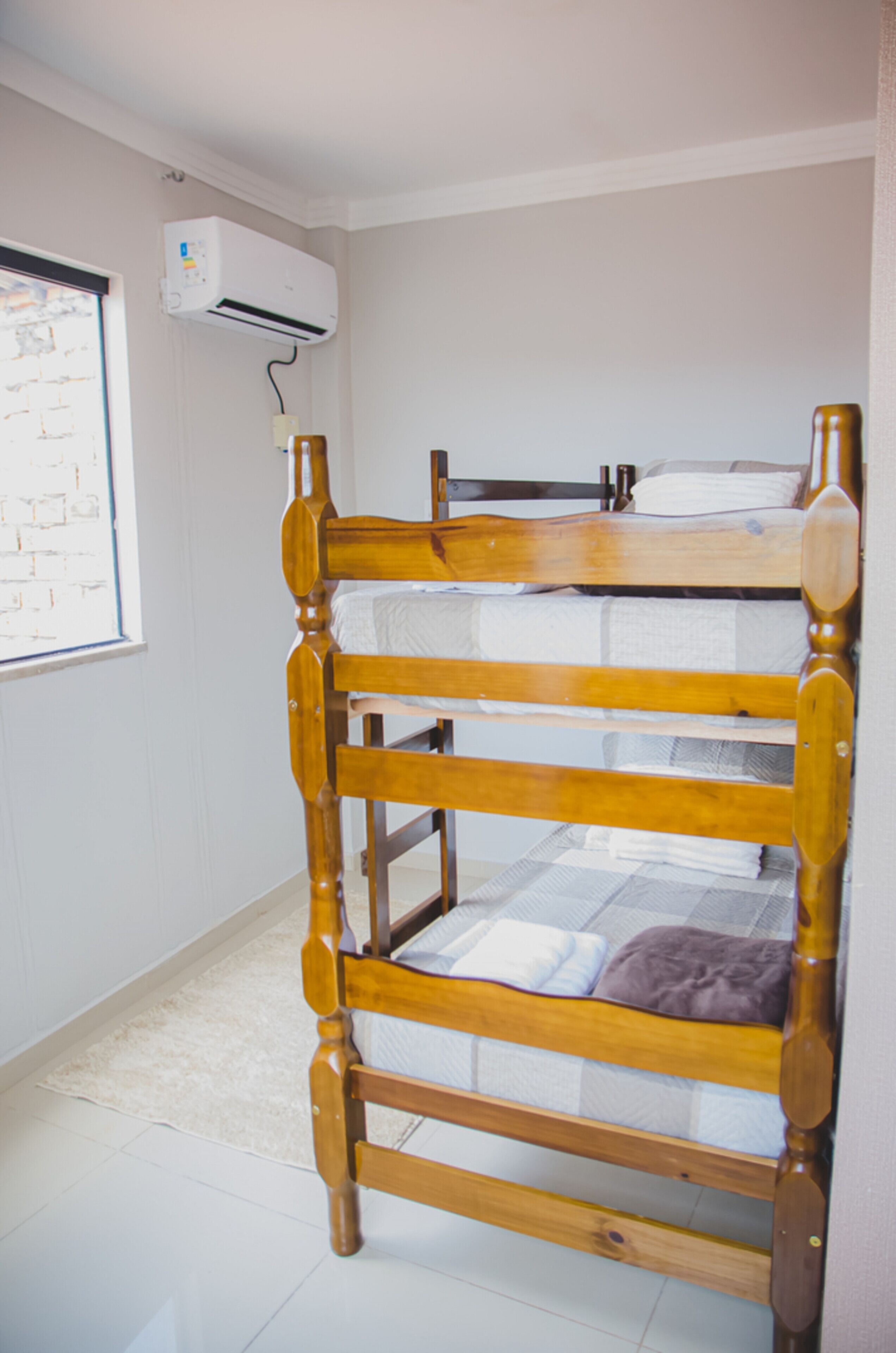 Un lit superposé avec une structure en bois et du linge de lit blanc.