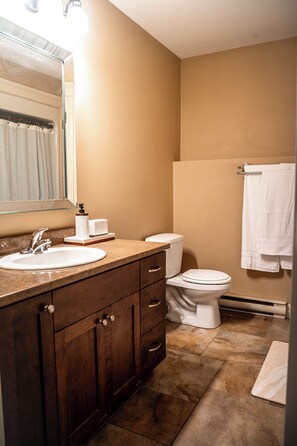 A bathroom with a sink, mirror, toilet, and towel rack.