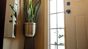 Ein Flur mit einem großen Fenster, einem Blumentopf und einer Tür.