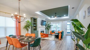 A spacious living area with a dining table, orange chairs, and a green sofa.