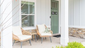 A porch with wicker chairs and a welcome sign.