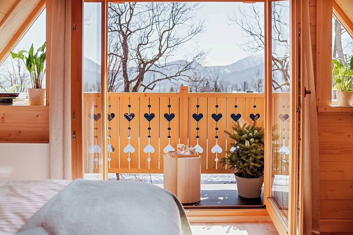 Une pièce chaleureuse avec un balcon en bois, une petite table sur laquelle se trouvent une tasse et une soucoupe, et une plante en pot.