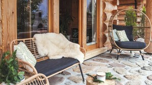 Un rincón al aire libre acogedor con muebles de mimbre y piso de piedra.