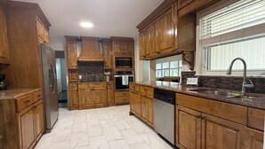 A kitchen with wooden cabinets, a stainless steel refrigerator, an oven, and a dishwasher.