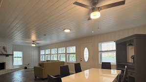 A spacious room with a large dining table, several chairs, a sofa, and a fireplace.