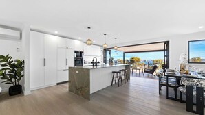 A modern kitchen with a marble island, white cabinetry, and pendant lighting. - Modern 4BR Mirraboo Home with Panoramic Lake Views (Mirrabooka)
