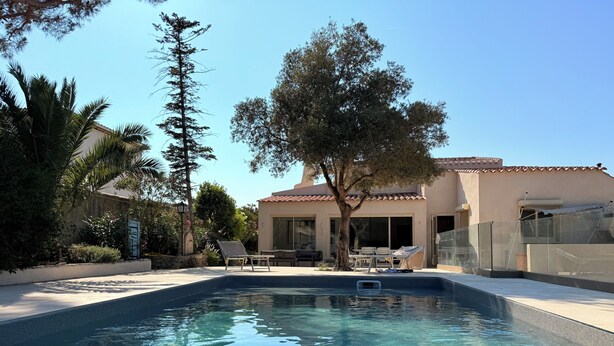 A swimming pool with lounge chairs and a pergola, surrounded by trees and a building with a tiled roof. - Maison Sud: Between sea and vineyards (Martigues)