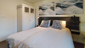 A bedroom with a bed, two patterned pillows, a nightstand, a wall-mounted lamp, and a wardrobe with a mirror. - 3 bedroom lovely home in Beesel (Beesel)