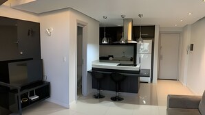 Una cocina moderna con una isla central, taburetes de bar e iluminación colgante.