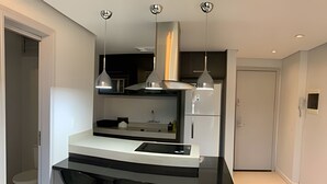 Una cocina moderna con una isla central, taburetes de bar, iluminación colgante y horno empotrado.