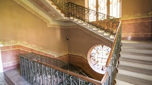 A grand staircase with ornate metal railings and a circular stained glass window at the top. - Casa Jolanda (Luino)