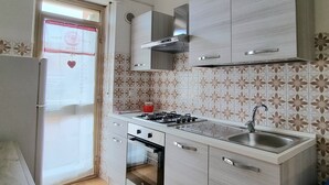 A kitchen with a gas stove, oven, sink, and decorative tiles. - Apartment in La Caletta 5 minutes from the beach (La Caletta)