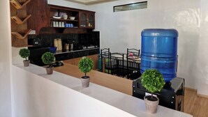Une cuisine moderne avec des meubles en bois, un plan de travail noir et un distributeur d’eau.