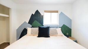 A bedroom with a bed, pillows, a nightstand, and a window.