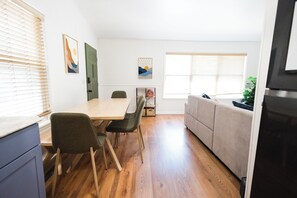 Una cocina moderna con zona de comedor, suelo de madera y una puerta verde.