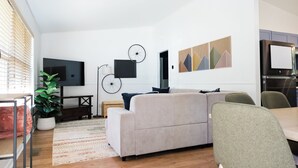 A modern living room with a sofa, a dining table, and a TV.