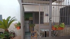 Una entrada protegida con macetas, una mesita pequeña y un refrigerador a la vista.
