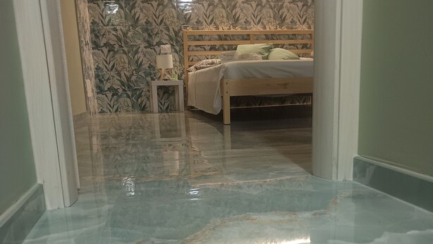 Un dormitorio con cama, mesita de noche y espejo.