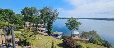 A lakeside property with a gazebo, a small building, and a chair.