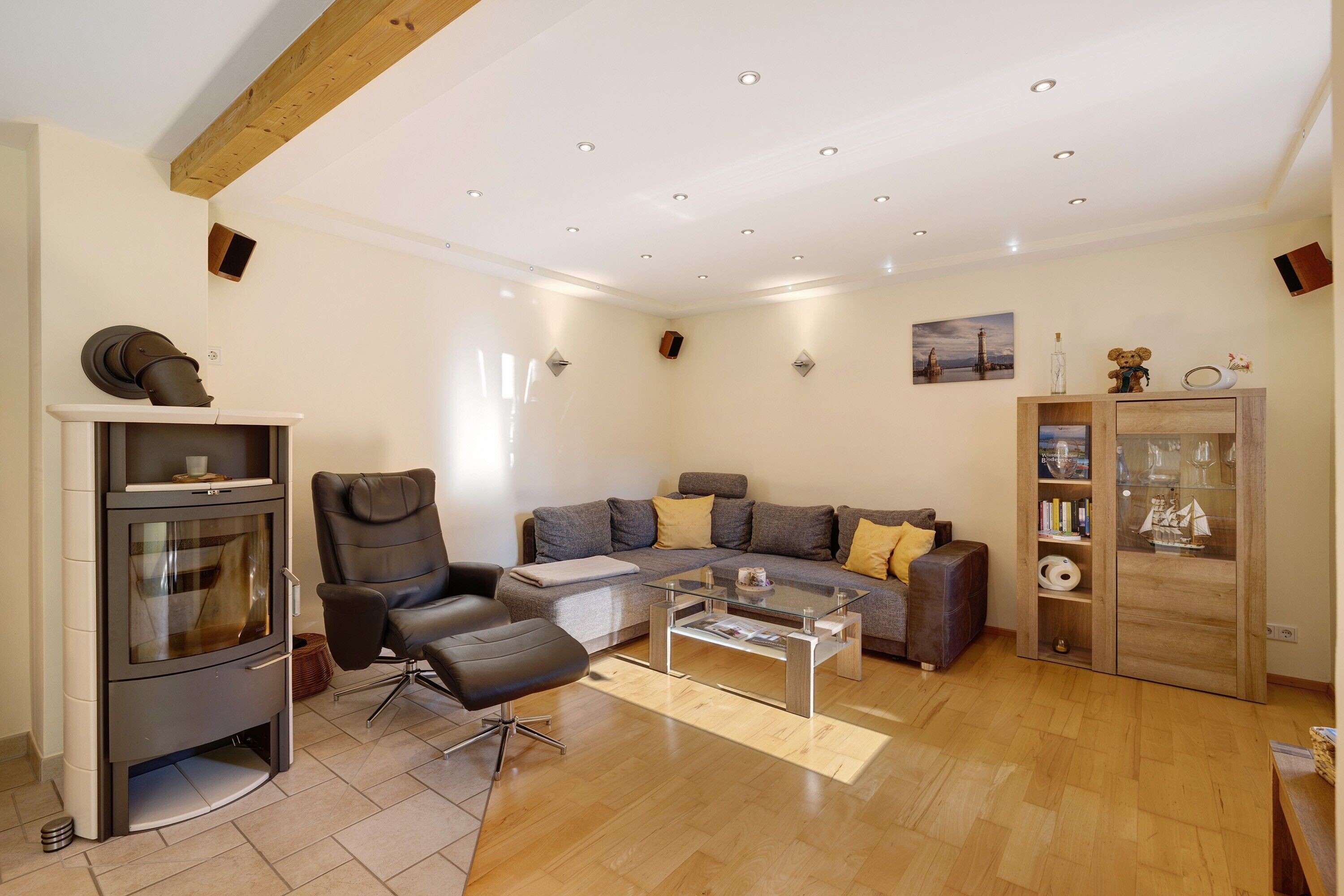 Ein modernes Wohnzimmer mit Sofa, Sessel, Glastisch und einer integrierten Unterhaltungseinheit.