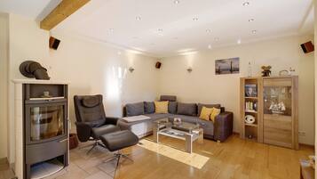 Ein modernes Wohnzimmer mit Sofa, Sessel, Glastisch und einer integrierten Unterhaltungseinheit.