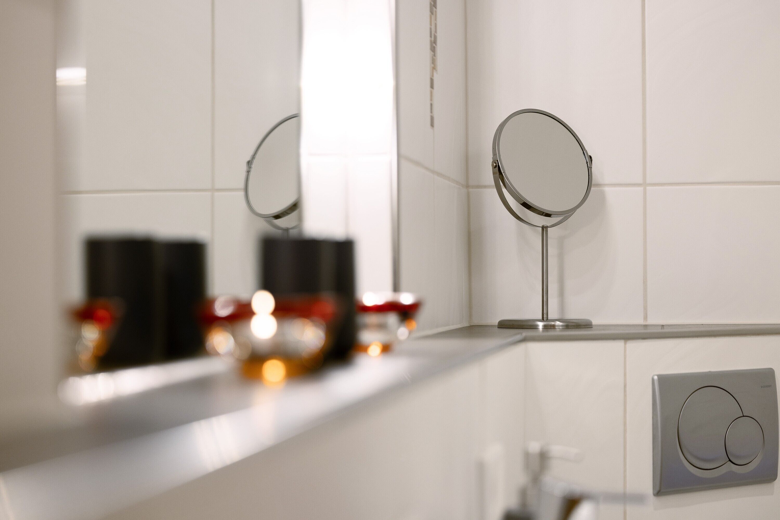 Een badkamer met witte tegels, een spiegel en een zeepdispenser.