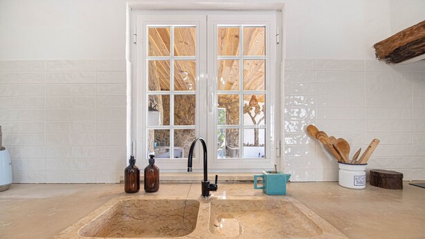 A kitchen with a large marble sink, a window with wooden frames, and a kitchen utensil holder. - Alma Alentejo Villa (Odemira)