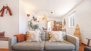 Uma sala de estar aconchegante com um sofá cinzento, um abajur de fibra e uma janela grande.