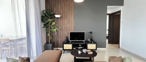 A modern living room with a sofa, a coffee table, a TV, and a plant.