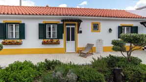 A two-story building with a tiled roof, green shutters, and a small balcony with flowers. - Aposento Real Villas (Montemor-o-Novo)