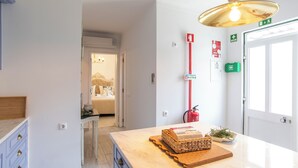 A kitchen with a marble countertop, a wooden cutting board with a cake, a fire extinguisher, and a green emergency kit on the wall. - Aposento Real Villas (Montemor-o-Novo)
