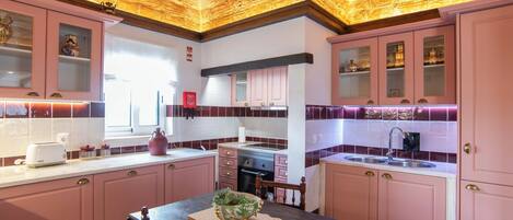 A kitchen with pink cabinets, a wooden ceiling, and a window.