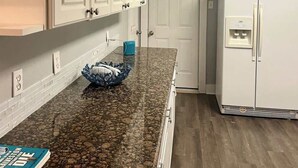 A kitchen with white cabinets, a granite countertop, and a white refrigerator. - 3 bedroom walk to the beach! (Galveston)