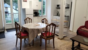 A dining area with a round table, four wooden chairs, and a red cushion on one chair. - Cosy apartment Ideal for hiking and nature (Laruns)