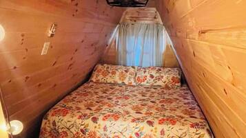 Een kleine, gezellige kamer met houten wanden en een bed met een bloemenprint.