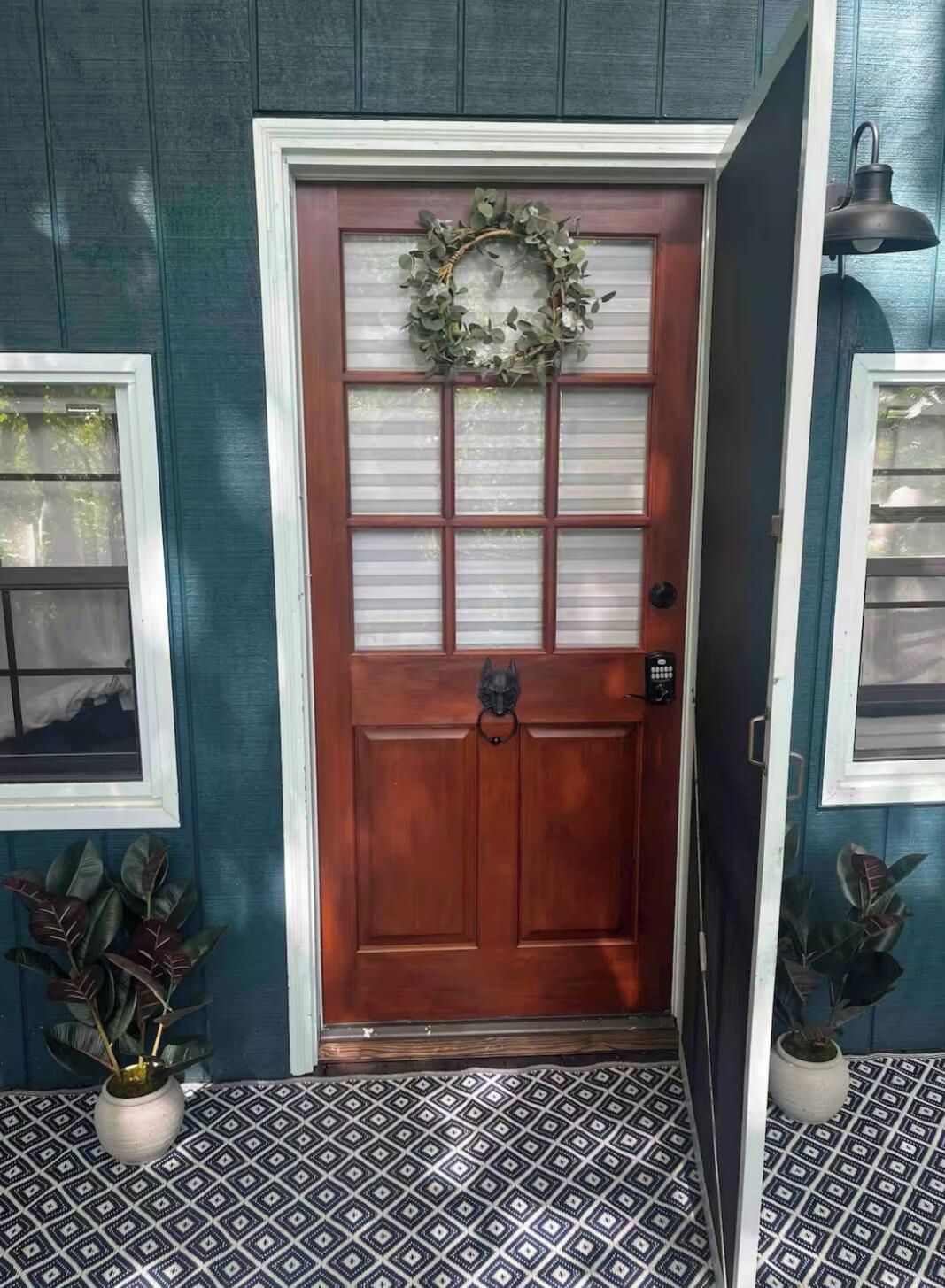 A wooden door with a frosted glass panel, a metal knocker, and a wreath above it.