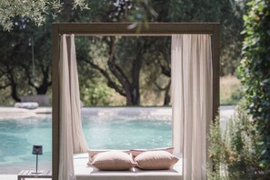 Ein Himmelbett mit Blick auf Pool und Bäume.