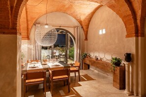 Un comedor con un arco de ladrillo, una lámpara colgante y vistas al exterior.