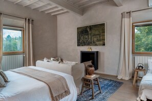 A bedroom with a large bed, a fireplace, a painting, and a view of trees through the window. - The Romantic Olive Reatreat with pool and garden near Florence (Lastra a Signa)