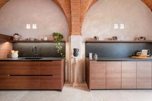 A kitchen with two wooden cabinets, a central island, and a brick archway.