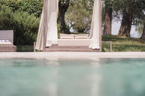 A canopy bed with a view of a pool and greenery. - The Romantic Olive Reatreat with pool and garden near Florence (Lastra a Signa)