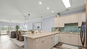 Una cocina amplia con una isla grande, armarios de colores claros y un salpicadero moderno.