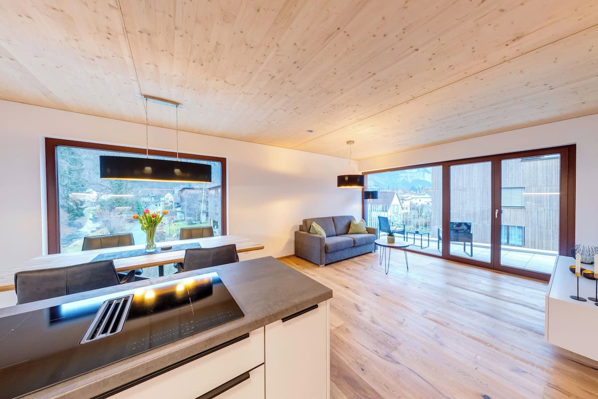 A modern kitchen with a built-in oven and a dining area with a table and chairs.