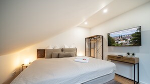 A bedroom with a bed, a bedside table, a TV, and a painting on the wall. - RAW-Flats Milse - Modern. Stylish (Bielefeld)