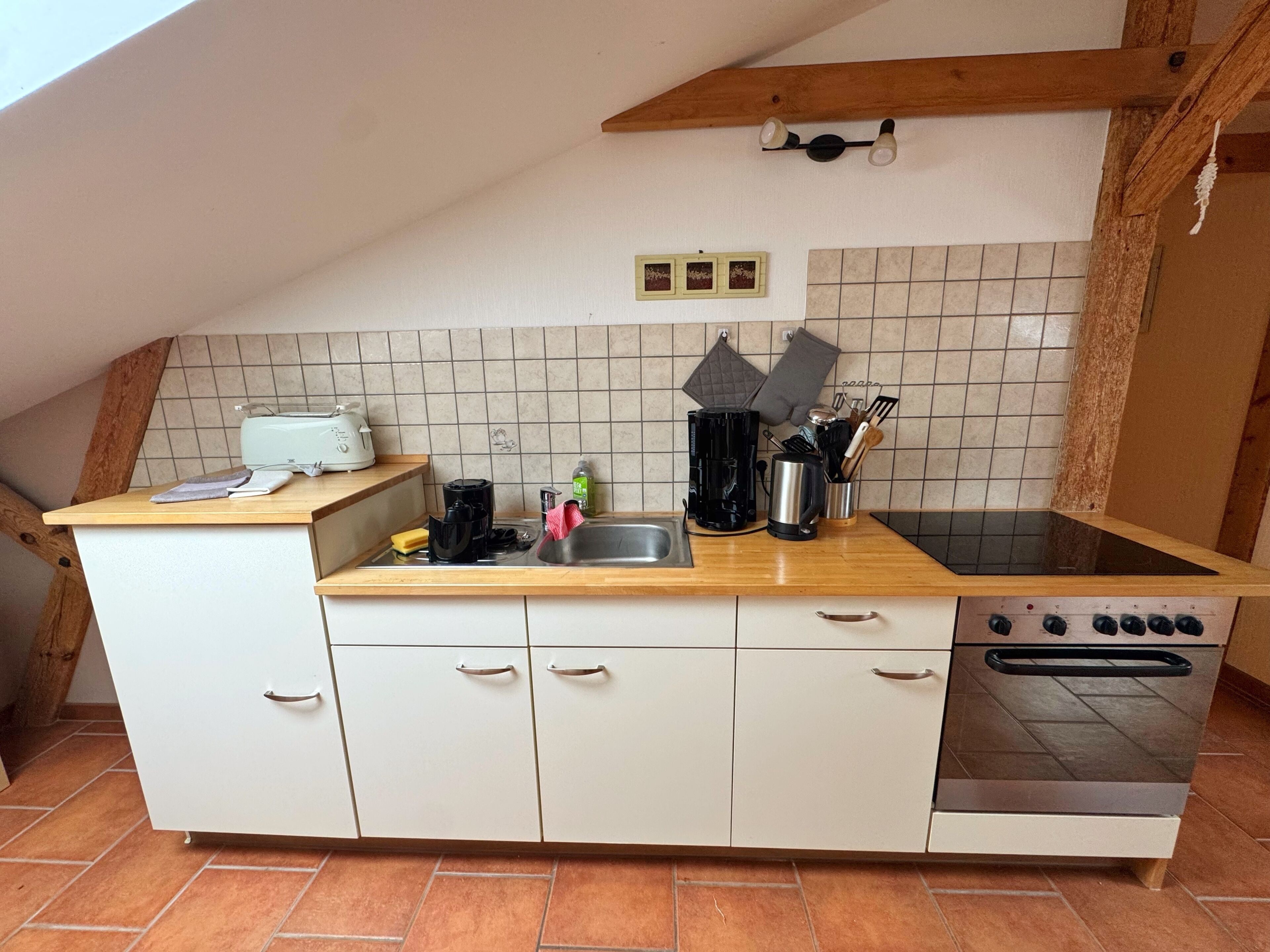 Een keuken met een inbouwoven, een spoelbak en een aanrecht met een broodrooster en koffiezetapparaat.