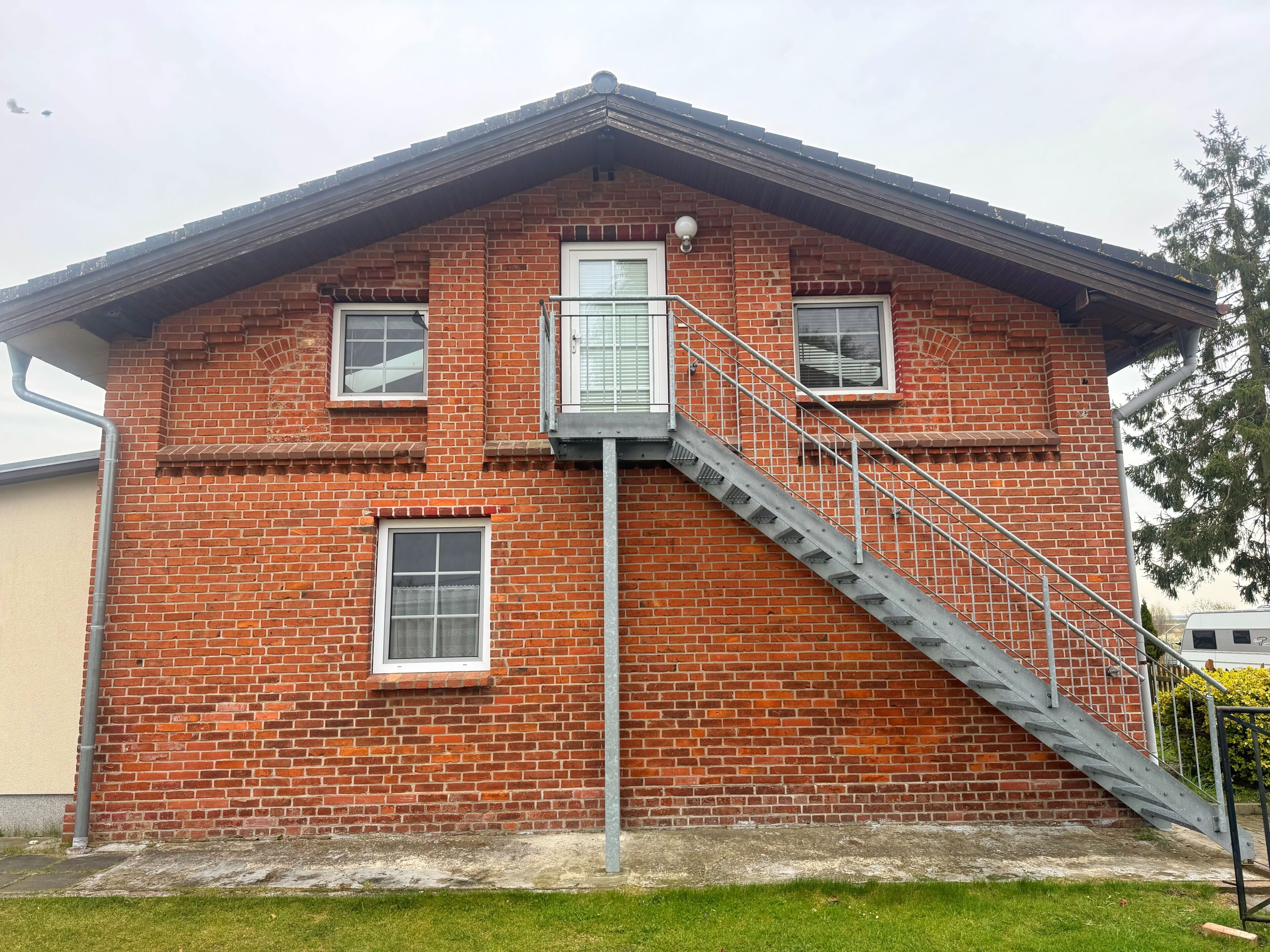 Een bakstenen gebouw met een metalen wenteltrap naar een raam.